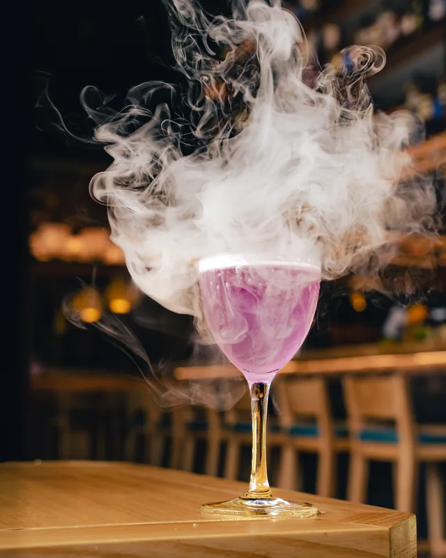 A pink cocktail beneath a cloud of smoke at Genki
