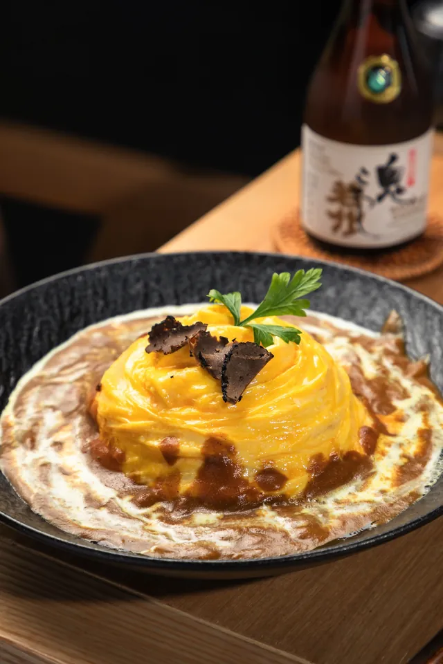 A folded golden omelet over rice with sauce